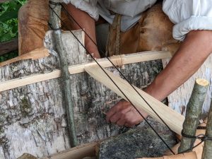 A historical interpreter constructing a birch bark canoe