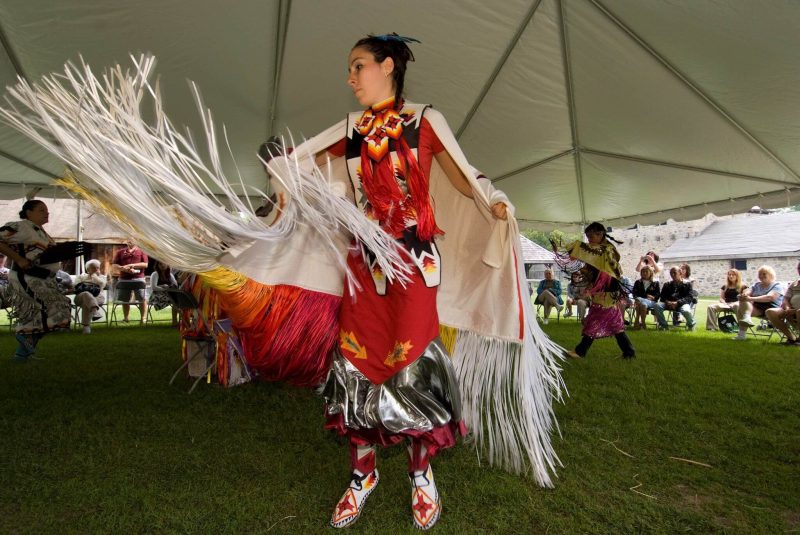 Une femme autochtone en habit cérémonial, dansant sous une tente a Sainte-Marie-au-pays-des-Hurons