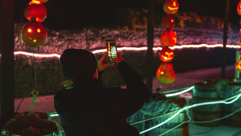 Person taking a picture of neon glowing pumpkin displays