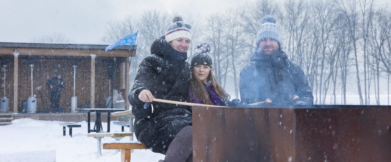 family roasting bannock over an open fire at Discovery Harbour