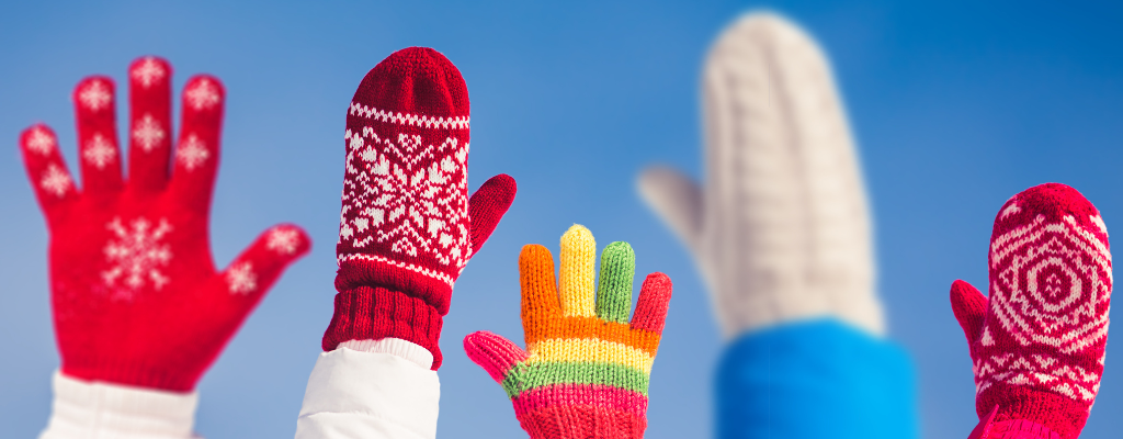 People holding up mittens and gloves in front of a blue sky