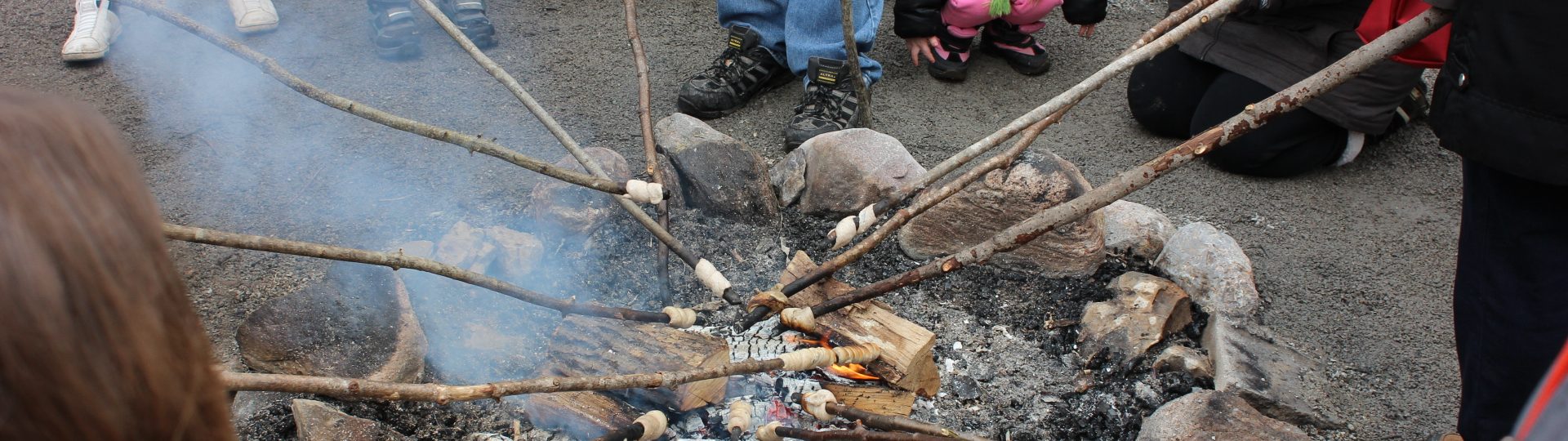 Guests making bannock over a fire