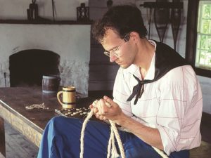 sailor tying knots while sitting on a table inside the Sailors’ Barracks
