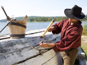 man seal cracks outside of an upside-down boat in the dockyard