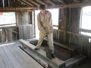 interpreter sawing large block of wood inside the sawpit
