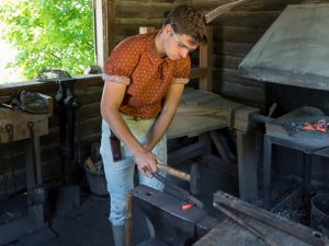 man hammering heated metal inside the Blacksmith Shop