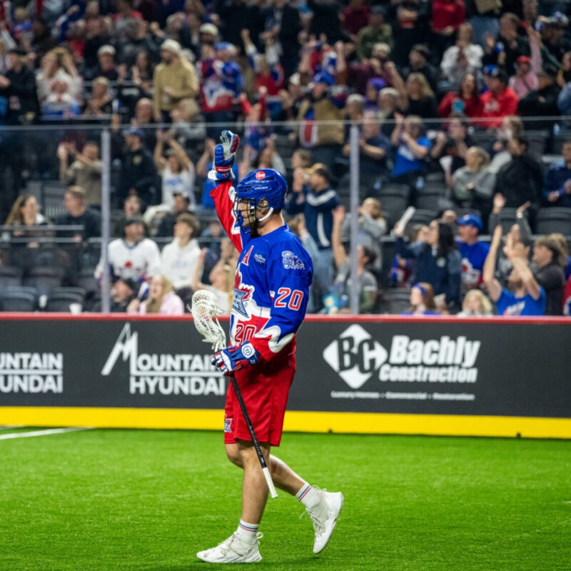 Chris Boushy du Toronto Rock debout avec un bâton de lacrosse devant un fond brillant